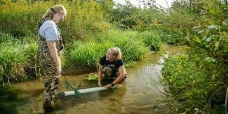 Researchers install water quality samplers in a stream.