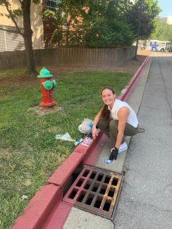Outreach Intern applies marker medallion next to storm drain.
