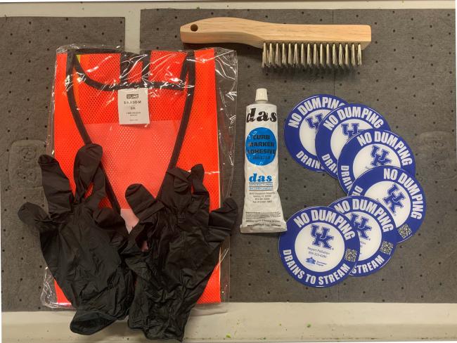 Safety vest, gloves, adhesive, wire brush, and storm drain medallions